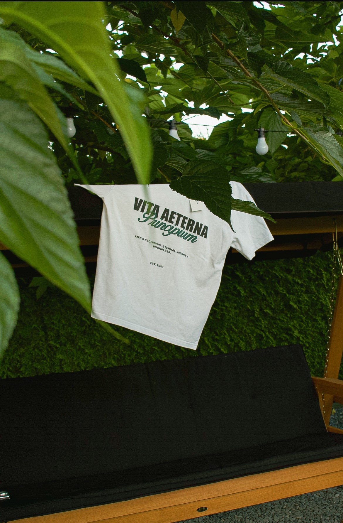 A T-shirt from the Vita Aeterna Principium colleciton hanging on a bench